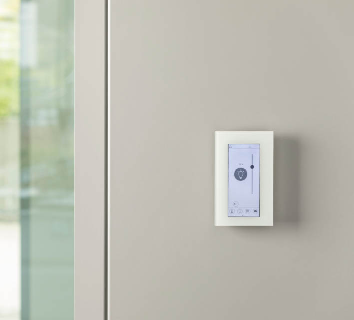 thanos EVO Raumbediengerät an einer Wand in einem Büroflur